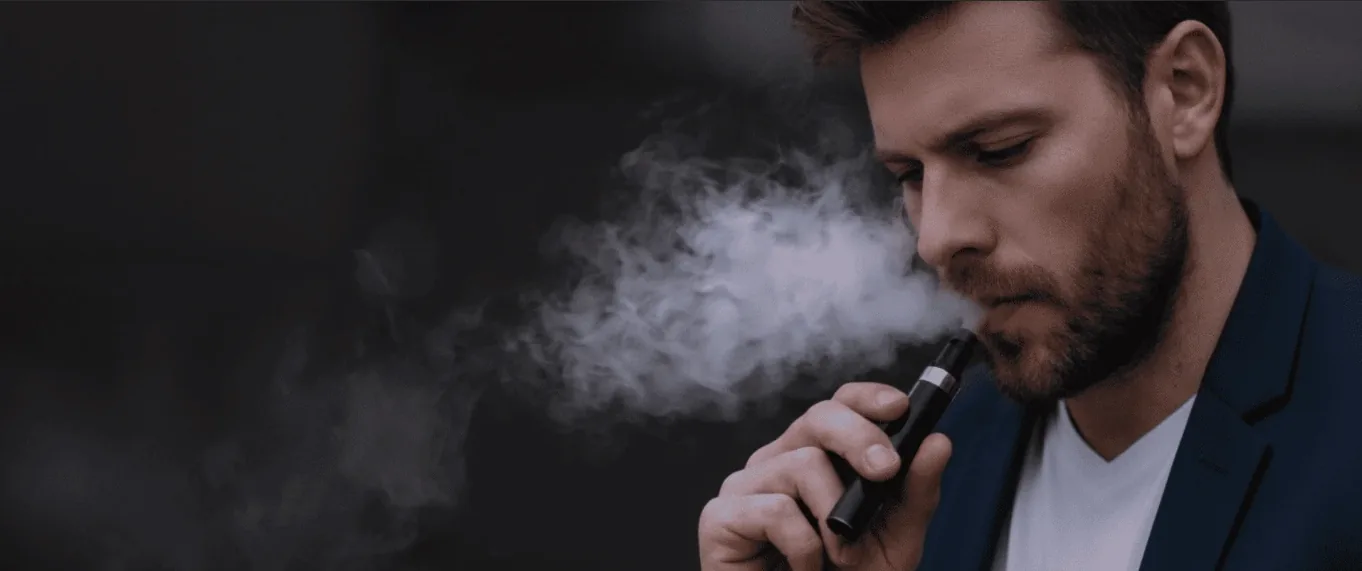 Man exhaling vapour in a dark room